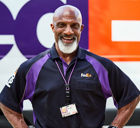 Smiling FedEx team member in a purple and black uniform