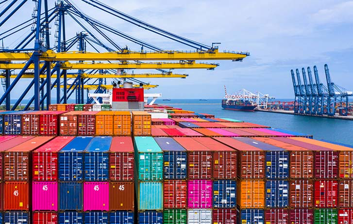 Aerial view of a global cargo port filled with multi-colored shipping containers and cranes
